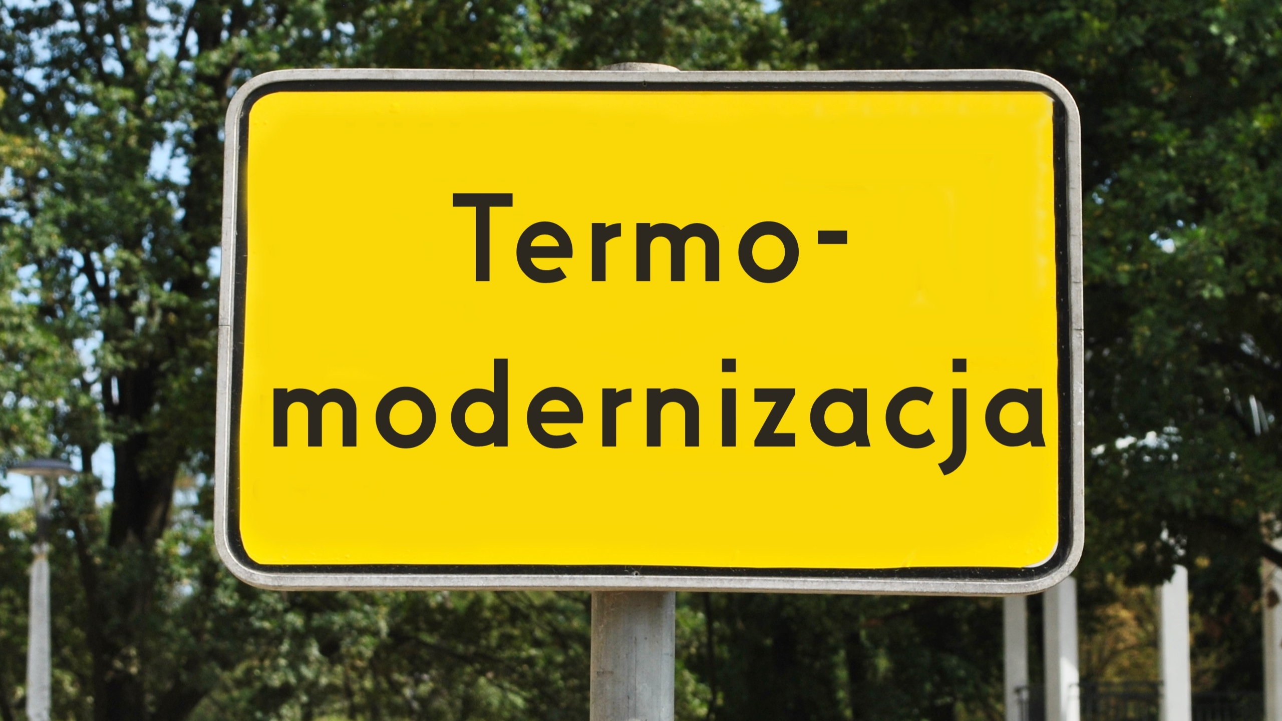 Żółty znak drogowy na tle lasu z napisem "Termomodernizacja"