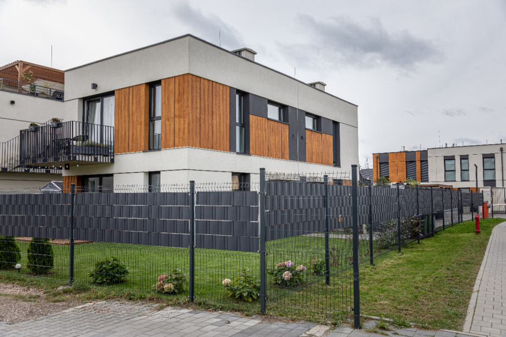 Kolorystyka i faktura elewacji: piaskowe odcienie z elementami drewna.